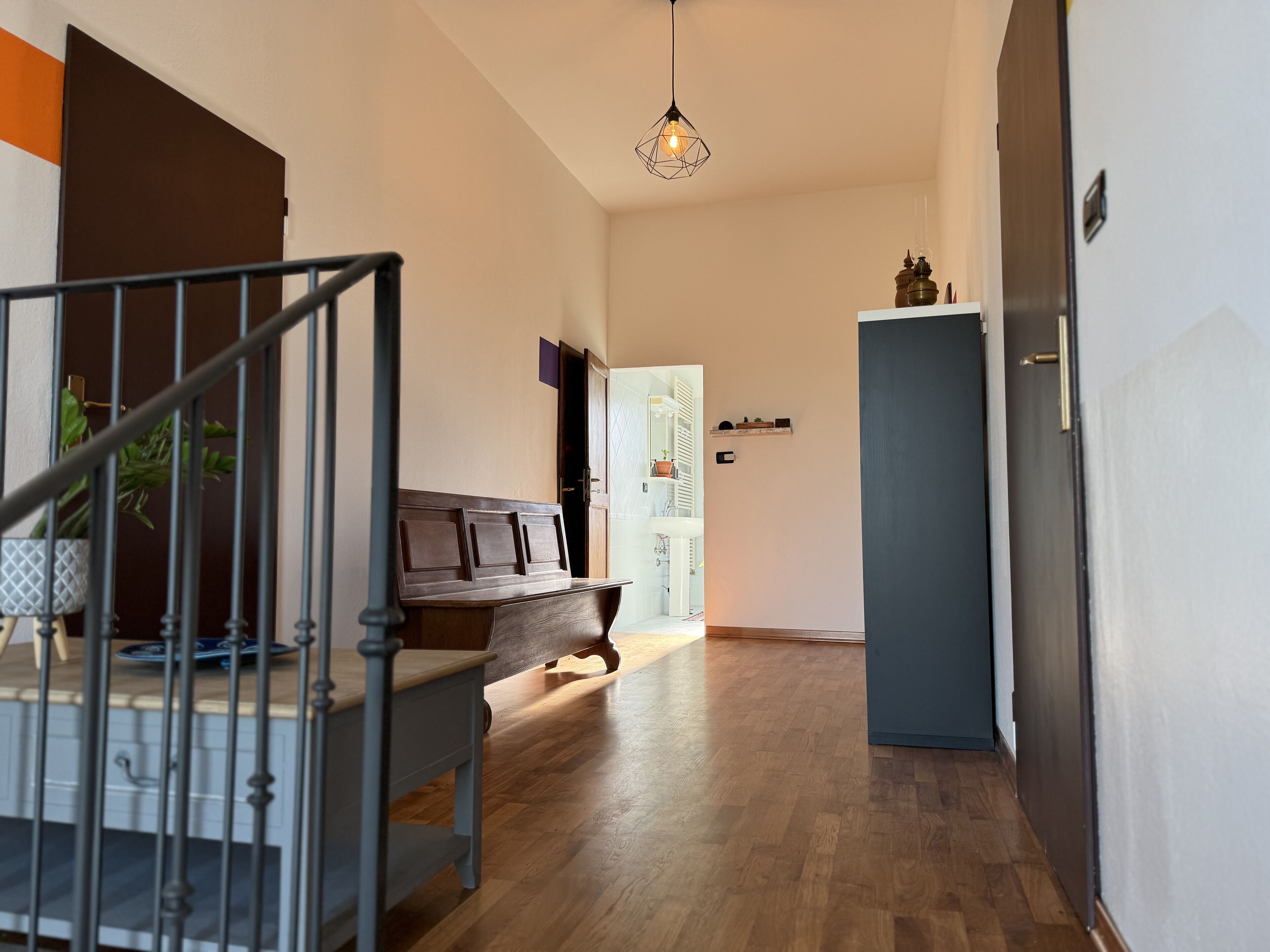 A modern interior with a staircase, wooden flooring, a blue cabinet, and a dining area with a table and chairs.