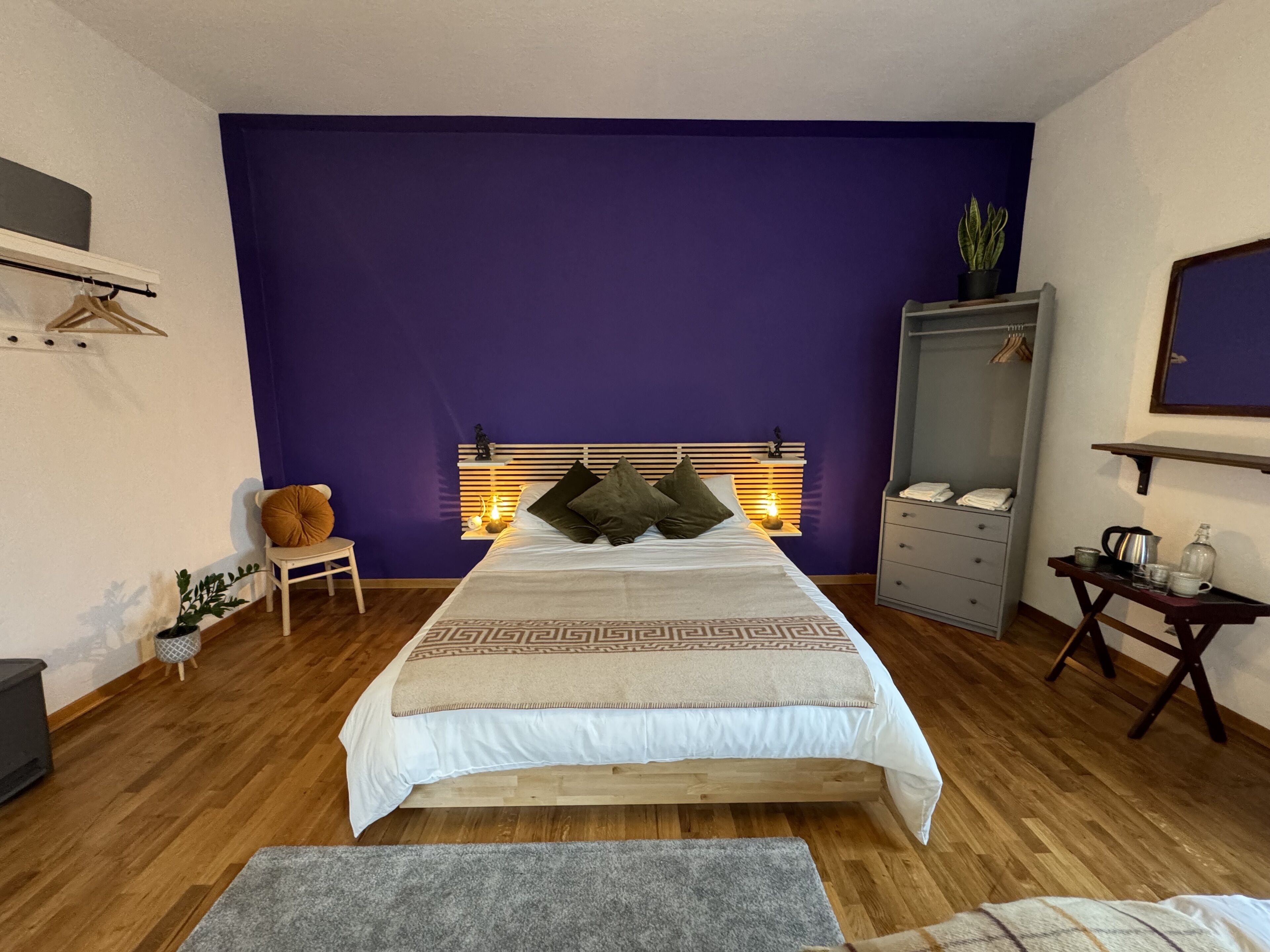 Ein Schlafzimmer mit Bett, Nachttisch, Kleiderschrank und einem kleinen Tisch mit Gegenständen.