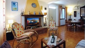 A living room with a fireplace, a television, and a dining area with a table and chairs.