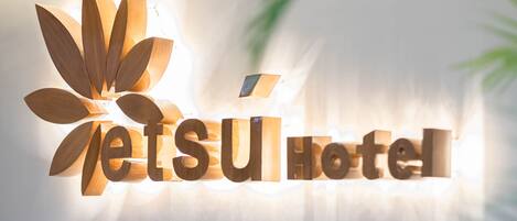 A wooden sign with the text "jetsu hotel" illuminated against a blurred background.