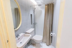 A bathroom with a toilet, sink, shower, and a mirror. - Etsu Hotel (Tacloban)