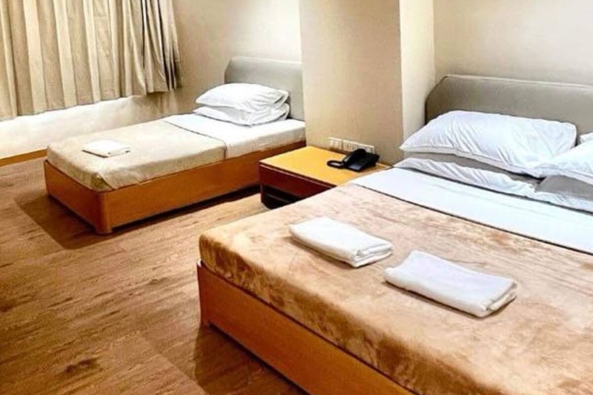 Ein Hotelzimmer mit zwei Einzelbetten, Holzboden, einem kleinen Tisch und einem Nachttisch.