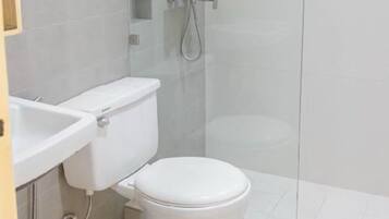 A bathroom with a toilet, sink, and glass-enclosed shower stall.
