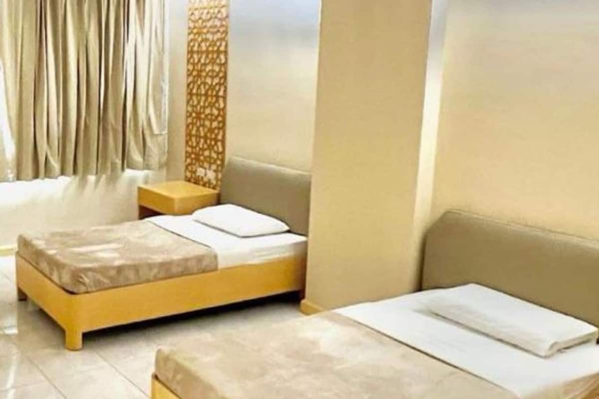 Ein Hotelzimmer mit zwei Betten, einem kleinen Tisch und einer dekorativen Wandverkleidung.