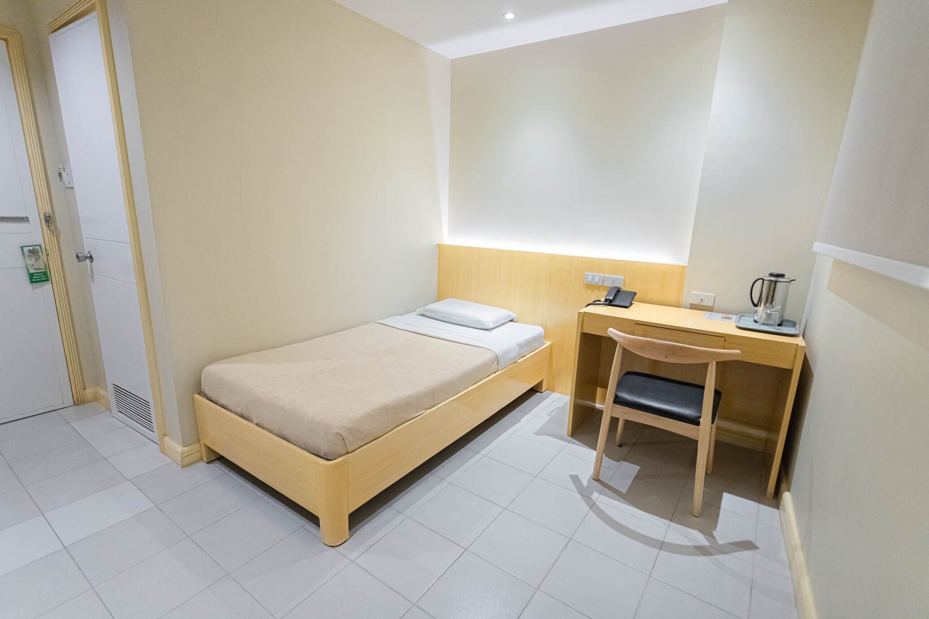 A small, clean room with a single bed, a desk, and a chair.