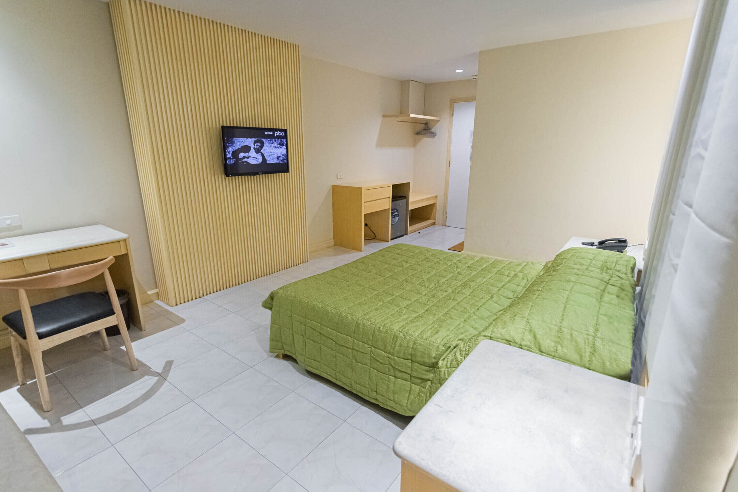 Une chambre d’hôtel équipée d’un lit, d’un bureau, d’une chaise, d’une télévision et d’une armoire.