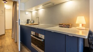 Une cuisine compacte dotée d’un four encastré, d’un évier et d’un petit plan de travail.