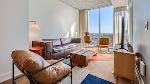 Ein modernes Wohnzimmer mit einer Ledersofa, einem Couchtisch und einem Fernseher auf einem Holzgestell.