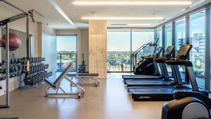 Ein modernes Fitnessstudio mit Laufbändern, Kraftgeräten und einem großen Spiegel.