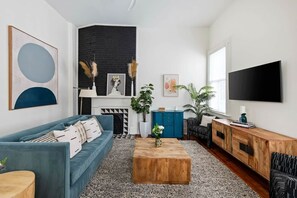 Un salon moderne avec un canapé bleu, une table basse en bois, un meuble bleu et un grand téléviseur.