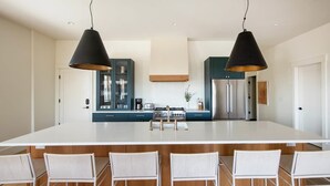 A modern kitchen with a large island, two pendant lights, and a dining area with four chairs. - Luxe 7bd, 6ba Retreat, Steps from King (Charleston)