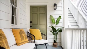 A porch with a white railing, a door, and a potted plant. - The OakTree | DT Charleston Gem - Near King Street (Charleston)