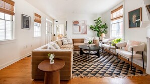 A spacious living room with a large sectional sofa, a round coffee table, and a patterned rug. - The OakTree | DT Charleston Gem - Near King Street (Charleston)