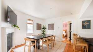 A spacious dining area with a long table and chairs, a fireplace, and a television mounted on the wall. - The OakTree | DT Charleston Gem - Near King Street (Charleston)