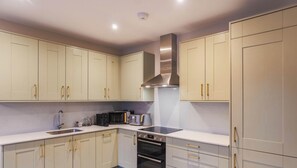 A modern kitchen with white cabinets, stainless steel appliances, and a built-in oven.