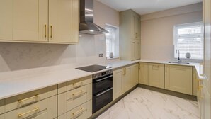 A kitchen with beige cabinets, a stainless steel range hood, a black oven, and a marble countertop. - 2BR Gem, Parking & Garden - VAT Q - By Tempstay (Berkshire)