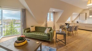 Un appartement moderne de style « loft », comprenant un coin repas, une cuisine et un canapé vert agrémenté de coussins décoratifs.