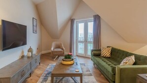 Un salon avec un téléviseur, un canapé, un fauteuil et une table basse.