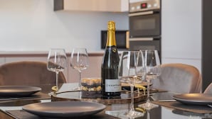 Une table à manger dressée avec des assiettes, des verres et une bouteille de champagne.
