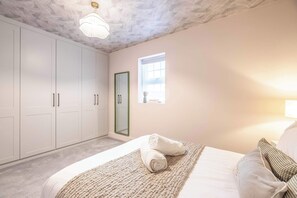 Ein Schlafzimmer mit Bett, Kleiderschrank, Fenster und Deckenleuchte.