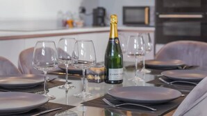 Tavola imbandita con piatti, bicchieri e una bottiglia di champagne in una cucina moderna.