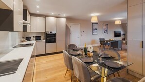 Una cucina moderna con zona pranzo, che include un tavolo in vetro, sedie e una piccola isola con un forno a microonde.