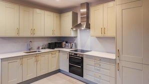 A modern kitchen with white cabinets, stainless steel appliances, and gold handles. - Castle Views| 2 Bed |Parking - VAT Q - By Tempstay (Berkshire)