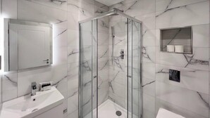 A modern bathroom with a glass-enclosed shower, a white sink, and a marble-tiled wall. - Chic 2 Bed Flat - Balcony - Parking - By Tempstay (Berkshire)