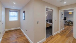 A spacious room with hardwood flooring, a large window, and a door leading to another room. - 1BR Gem, Private Parking - VAT Q - By Tempstay (Berkshire)