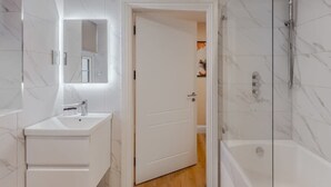 A modern bathroom with a marble sink, a glass-enclosed shower, and a door leading to another room. - 1BR Gem, Private Parking - VAT Q - By Tempstay (Berkshire)
