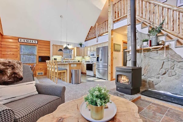 Un interior acogedor con chimenea, paredes de madera, una cocina y una escalera.