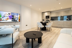 A modern living room with a flat-screen TV, a round coffee table, and white sofas. - Nuvola Suite I Luxury 1BR Apartment I Sky Views (Greater Manchester)