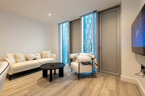Ein modernes Wohnzimmer mit einer Couch, einem Sessel, einem Couchtisch und einem Fernseher.