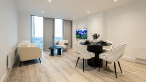 Un salon moderne avec un canapé, une table à manger et des chaises, ainsi qu’un téléviseur fixé au mur.