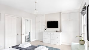 Ein modernes Schlafzimmer mit Bett, Kommode, Fernseher und Kleiderschrank.