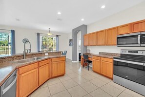 Una cocina moderna con armarios de madera, encimeras de granito, electrodomésticos de acero inoxidable y una isla grande.