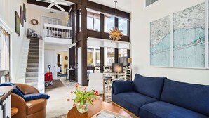 A spacious living room with a blue sofa, a brown leather chair, and a wooden coffee table with a vase of flowers. A large map is displayed on the wall. - Lido Beach Coastal Escape Near Beach (Sarasota)