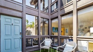A modern building with a blue door, large windows, and outdoor seating area with wicker chairs. - Lido Beach Coastal Escape Near Beach (Sarasota)