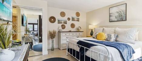 A bedroom with a bed, bedside table, lamp, and wall decor.