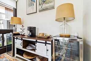 Une petite cuisine équipée d’une machine à café, d’un bocal en verre et d’un panier posé sur le comptoir.