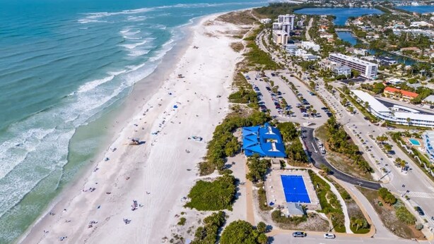 An aerial view of a coastal area with a beach, a parking lot, and buildings. - Lido Beach Coastal Escape Near Beach (Sarasota)