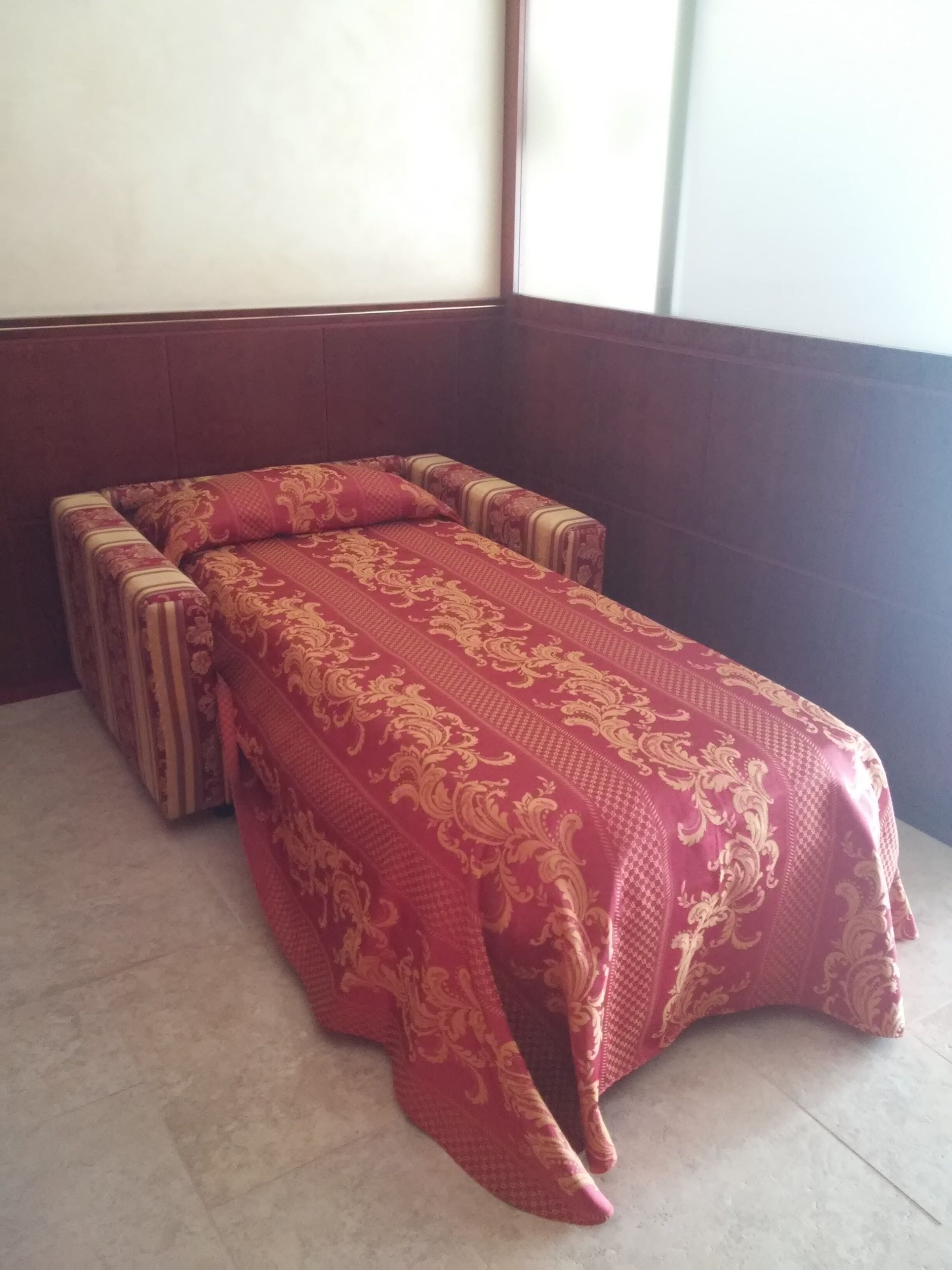 Una habitación con una mesa de masajes cubierta con un paño estampado en rojo y dorado.