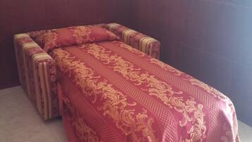 Una habitación con una mesa de masajes cubierta con un paño estampado en rojo y dorado.