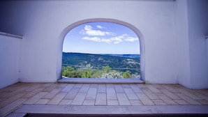 A room with a view through an arched window overlooking a hilly landscape. - Hotel Relais dei Normanni (Monte Sant'Angelo)