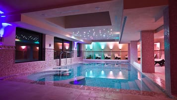 Relax by the pool surrounded by a mosaic tile pattern and lounge chairs.
