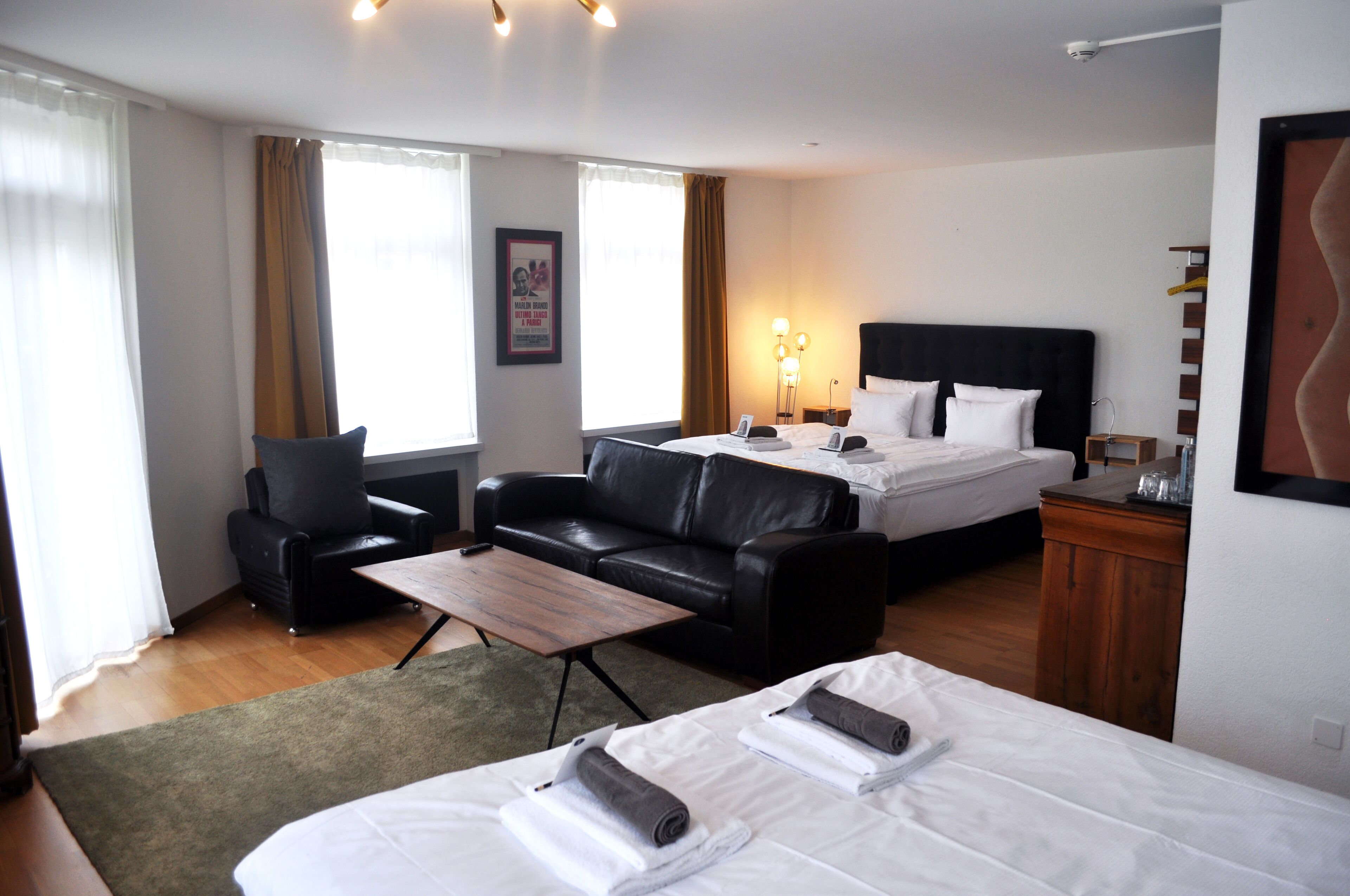 Una habitación de hotel con una cama, un sofá, una mesita, un escritorio y una lámpara.
