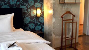 Habitación de hotel con cama, mesita de noche, escalera de madera y pared con papel tapiz floral.