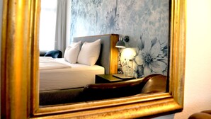 A hotel room with a bed, a nightstand with a lamp, and a floral wallpaper. - Guesthouse fürDich (Zürich)