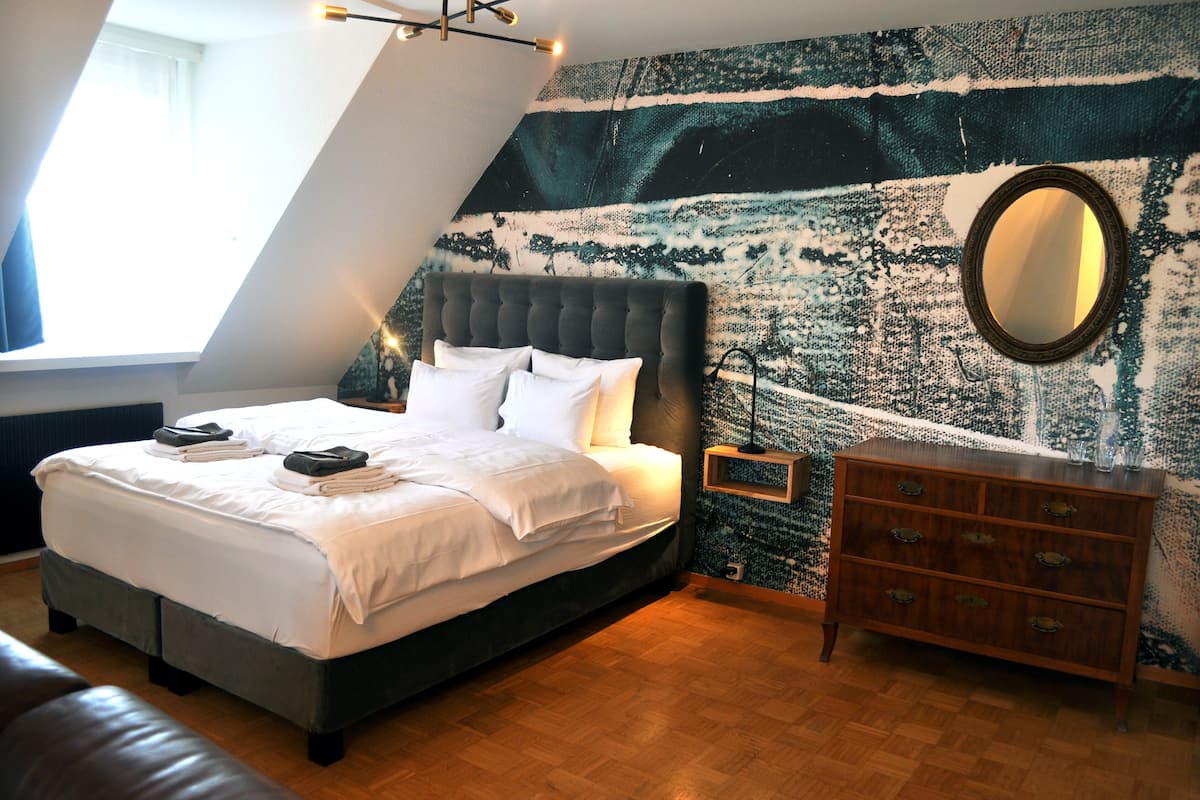 A bedroom with a bed, a dresser, and a wall tapestry.