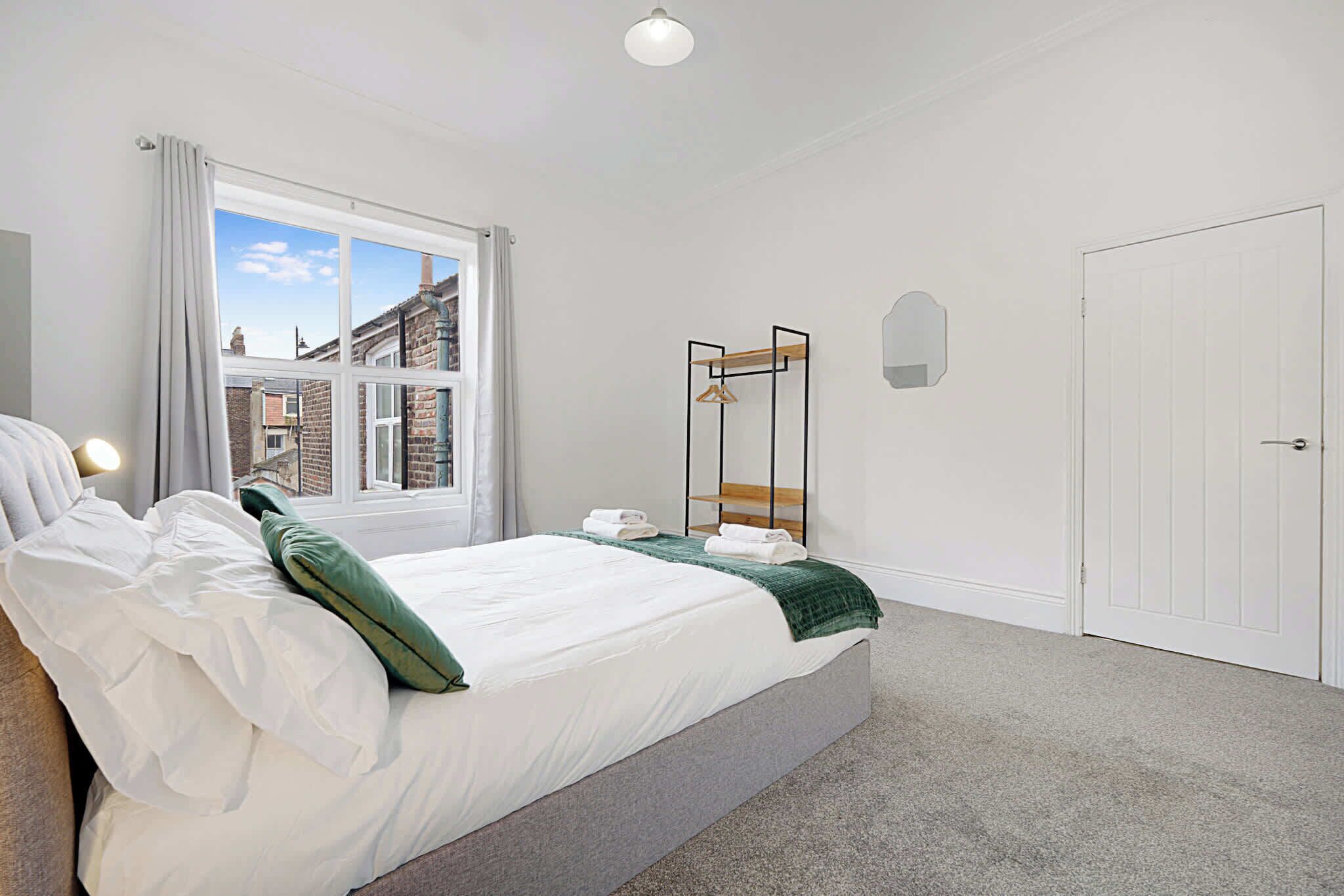 A bedroom with a bed, a window, a wardrobe, and a door.